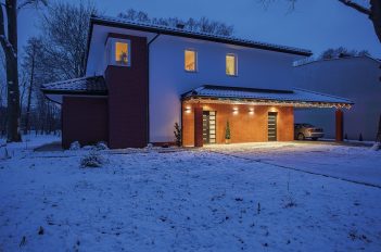 Die Außenansicht eines schneebedeckten Hauses in der Dämmerung, innen brennt Licht