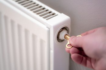 Eine Hand beim Entlüften eines Heizkörpers mit einem Entlüfterschlüssel
