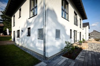 : Einfamilienhaus mit Lüftungsgittern in der Fassade für eine innenaufgestellte Luftwärmepumpe