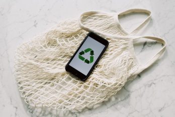 Handy mit grünem Recyclingschild auf einer Netztasche